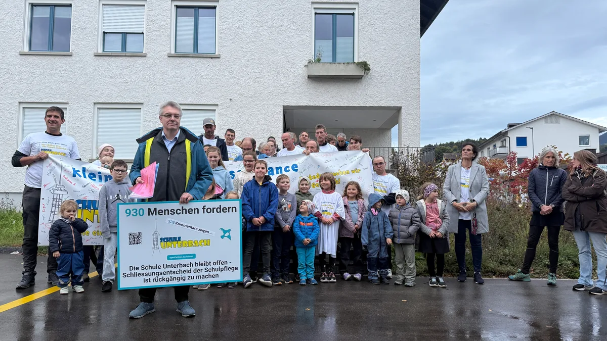 Ein Mann mit einem Schild steht vor einer Gruppe Menschen.